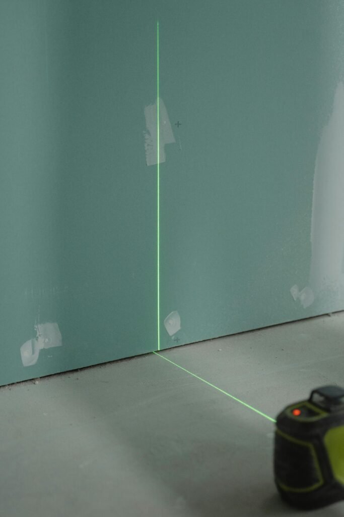 Laser alignment tool projecting light on a wall for precise measurement in construction.